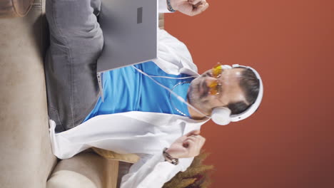Vertical-video-of-Man-looking-at-laptop-is-happy-and-dancing.